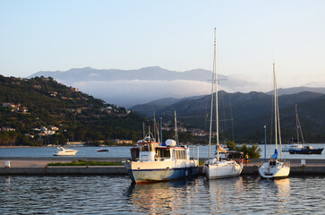 Fototapeta premium Boats and yachts in harbor with mountains and clouds at sunset