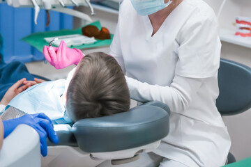 doctor demonstrates how to care for teeth on a special medical jaw in a dental office to a child....