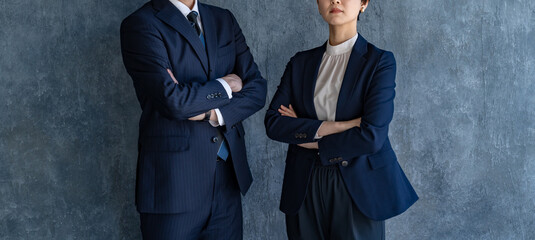腕組みをするスーツを着た男女