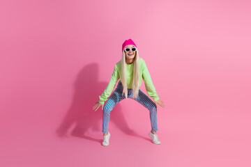 Fashionable young woman posing confidently in a bright outfit with a pink background, exuding...