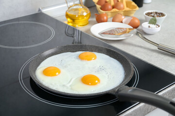 Cooking tasty eggs on frying pan in kitchen, closeup