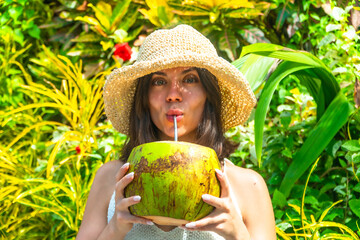 Tourist enjoying tropical vacation, sipping fresh coconut water in lush greenery of siargao island