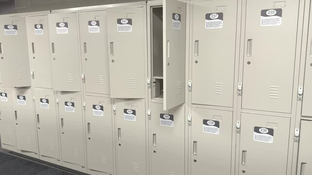 A calm, empty gym room with rows of closed wooden lockers under soft lighting, creating a calm atmosphere. Empty gym locker room with rows of metal lockers