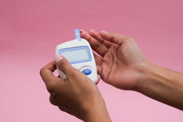A person using a digital glucose meter to check blood sugar levels,indicative of diabetes management or hypoglycemia monitoring