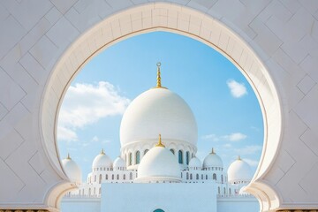 Naklejka premium Grand Mosque in Abu Dhabi, with a white dome visible through an archway, against a blue sky background