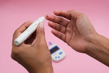 A person using a digital glucose meter to check blood sugar levels,indicative of diabetes...