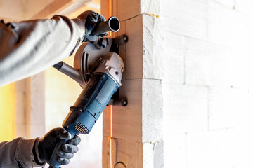 Construction worker cutting aerated concrete blocks with angle grinder