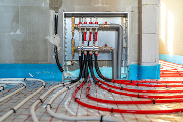 Underfloor heating system manifold with pipes distributing hot water for home interior