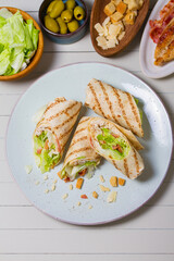 Turkey wraps on a plate and ingredients on a table. Tortilla, burritos, sandwiches, twisted rolls. High angle view