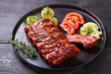 Rack of ribs with potatoes on black plate and coleslaw