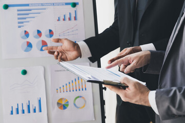 Businessman making a presentation at work in front of colleague. Businessman coach mentor explain graph chart on flipchart corporate group workshop training in meeting room.