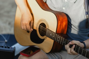 Young caucasian male playing acoustic guitar outdoors