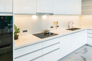 Modern minimalist kitchen design with sleek white cabinetry, shiny surfaces, and organized workspace