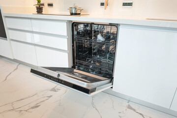 Modern kitchen interior featuring an opened dishwasher with stainless steel finish and marble...