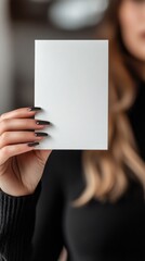 Naklejka premium Woman holding blank card, soft focus background, indoor setting