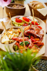 A charcuterie board featuring a variety of cured meats, sliced cheeses, and fresh salad with cucumbers, tomatoes, and red onions.