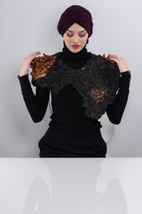 A stylish Muslim woman in a hijab presents her innovative handmade fashion accessory crafted from...