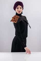 A stylish Muslim woman in a hijab presents her innovative handmade fashion accessory crafted from...
