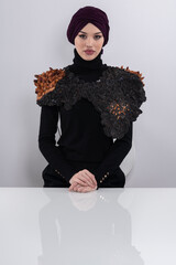 A stylish Muslim woman in a hijab presents her innovative handmade fashion accessory crafted from...