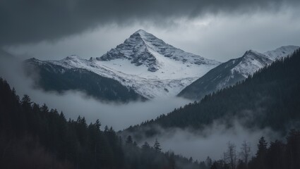Obraz premium Dark atmospheric landscape featuring a forested snowy mountain enveloped in low clouds. Gloomy overcast scenery showcases towering mountains with forest and snow beneath a low lead gray sky. Bleak ...
