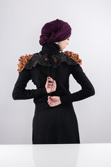 A stylish Muslim woman in a hijab presents her innovative handmade fashion accessory crafted from...