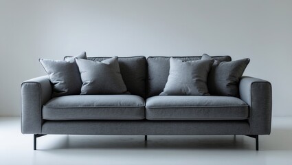 Naklejka premium Modern gray sofa with cushions positioned against a white background.