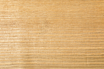 The texture of natural hardwood is illuminated by bright sunlight. The structure and pattern of the wood are clearly visible.