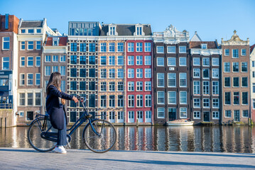 Une femme sur un vélo en face des maisons dansantes dans la ville de Amsterdam au pays-bas 