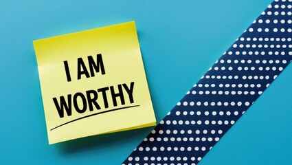 Note stick on a blue background with text I AM WORTHY, representing self-talk affirmation to boost low self-esteem and encourage self-love and acceptance of personal value.