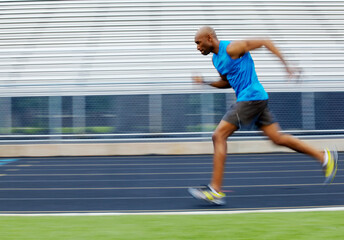 Fototapeta premium Motion blur, race track and man running with speed for sports competition, exercise and fitness workout. Outdoor, stadium and fast African athlete sprint for cardio, energy and athletics training