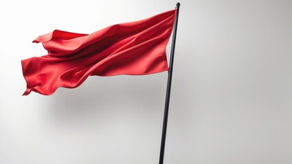 Red Flag Fluttering in the Wind on Pole Set Against a White Background.