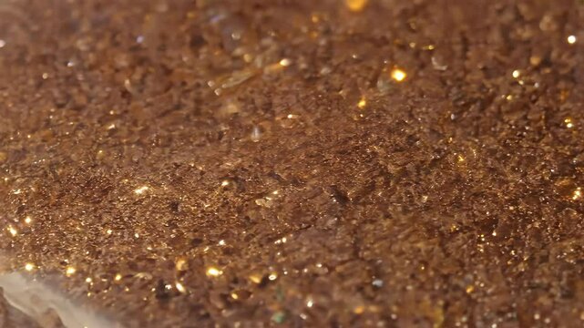 Close-up of a Bronzite texture background brown surface with sparkling golden flecks.