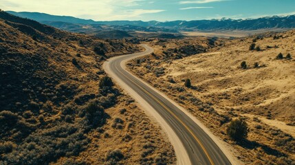 Naklejka premium A winding road curves through a mountainous desert landscape scene