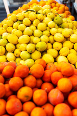 Mandarins, lemons, and oranges are stacked in a crate for sale at the market.