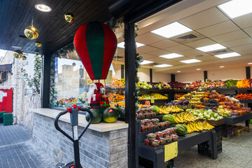 Naklejka premium Haifa, Israel – March 7, 2025, A vegetable shop decorated with Santa Claus dolls on a hot air balloon for Christmas. Horisontal frame