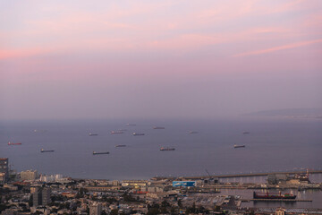 Haifa, Israel – March 7, 2025, View from Louis Promenade of the lower city, port, and sea with ships waiting for unloading at twilight under the full moon.