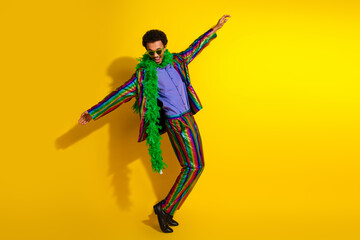 Colorful young man in a vibrant suit enjoying dance moves against a bold yellow backdrop, showcasing charisma and energy
