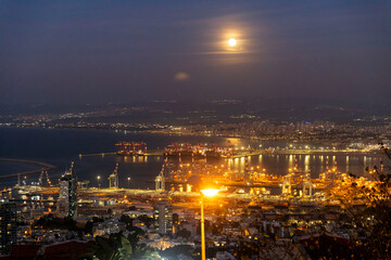 Obraz premium Haifa, Israel – March 7, 2025, View from Louis Promenade to the lower city and port at twilight under the full moon.