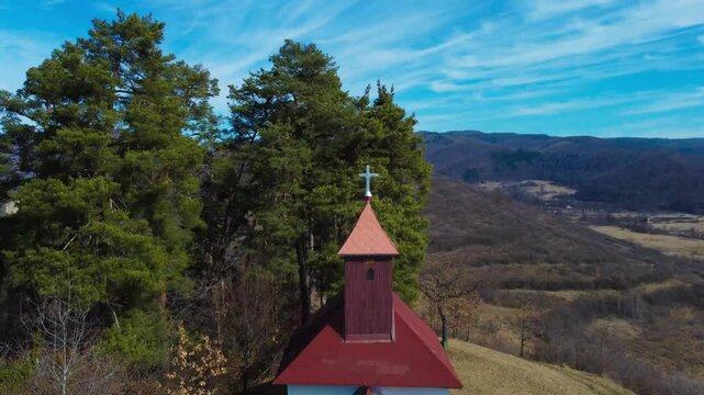 A pull-back aerial shot of the 14 Crosses Catholic Chapel in Sovata - Romania. A small isolated church on a hill