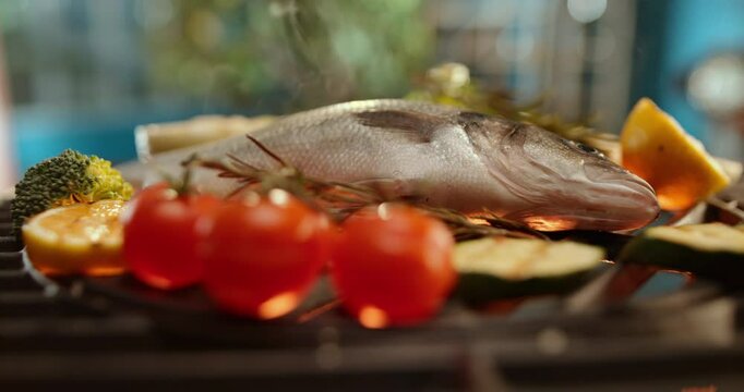 Sea bass fish grilling on outdoor barbecue, seasoned with lemon slices, emitting smoke and aroma. Cooking healthy food