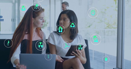 Image of ecology icons over diverse colleagues discussing work in office