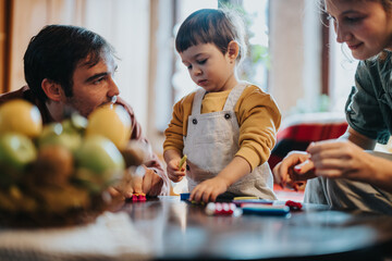 A family is spending time together at home, engaging in activities that foster creativity and...
