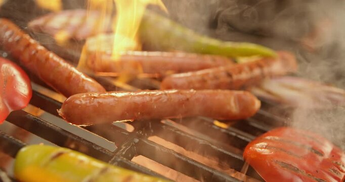 Extreme close-up footage of an unknown chef grilling sausages on a charcoal grill in slow-motion