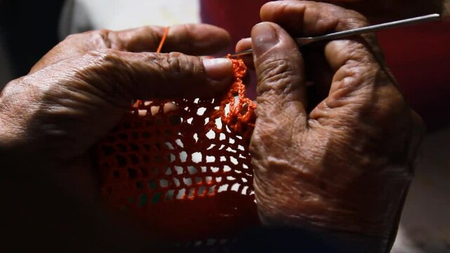 Detail of the hands of a latina woman while she is knitting a wool dress in a workshop in Yaguara - Huila - Colombia. Concept of art, work and old age