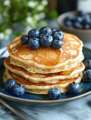 Stack of Delicious Pancakes Topped with Fresh Blueberries on a Blue Plate in Natural Light Setting
