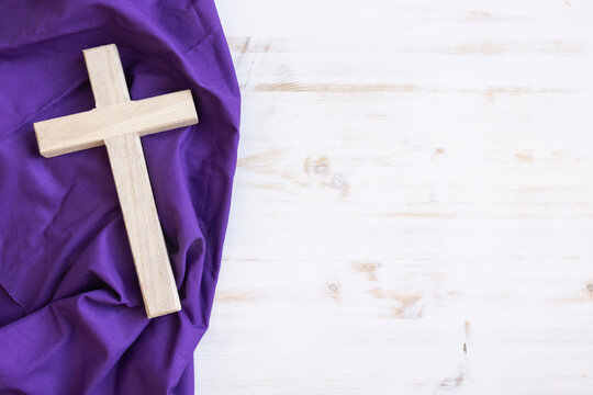 Wood cross on a purple cloth with a white wood background and copy space