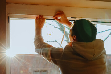 One person glues special rubber to the window frame.
