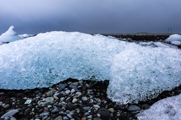 Icebergs melting on diamond beach, iceland, under cloudy sky