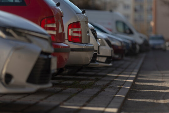 A long row of various cars is neatly parked in a spacious parking lot, showcasing the diversity of vehicles available today