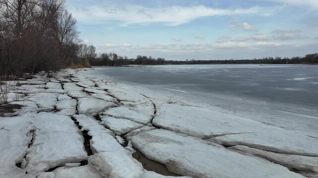 slow motion video winter landscape on frozen lake. cracked ice on river. Bird watching in the wild. Slow motion video in 4k. Hand held video of lake shore frost winter cold wether
